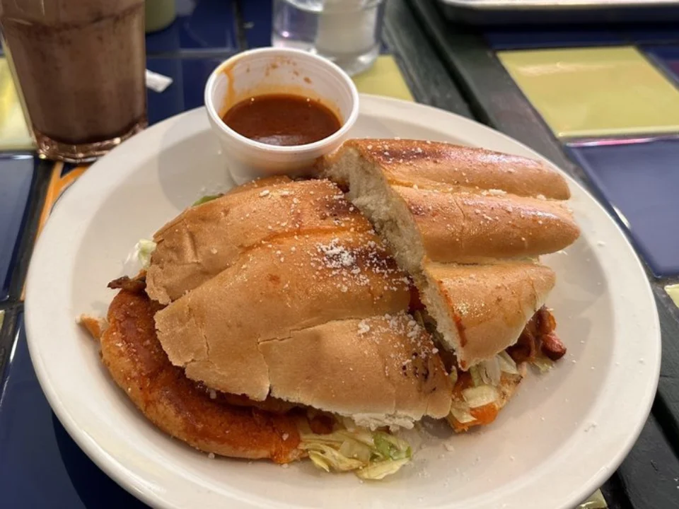 Birria Torta - Mexican sandwich stuffed with tender birria beef, cheese, and fresh toppings.