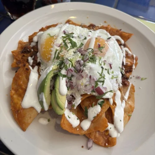 Chilaquiles - Crispy tortilla chips simmered in salsa verde or roja, topped with crema and cheese.