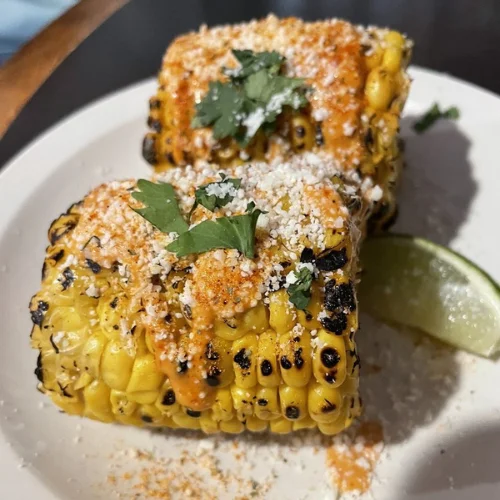 Elote De Calle - Classic Mexican street corn on the cob with butter, mayo, cheese, and chili.